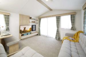 Craig Tara Holiday Park caravan living room with grey sofas, big windows and a TV