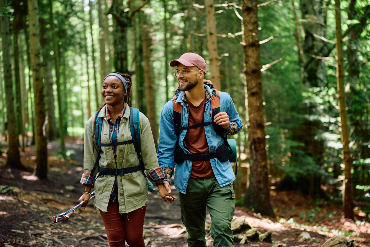 Stay at Parkdean resorts in England near walking trails. | Image of a happy man and his girlfriend hiking in the forest | 