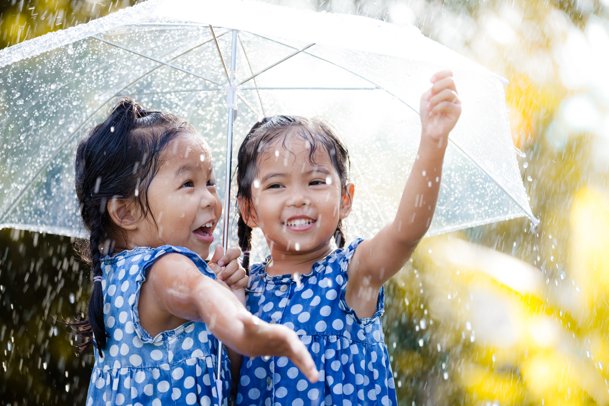 rainy day activities | Two happy asian little girls with umbrella having fun to play with the rain together in vintage color tone