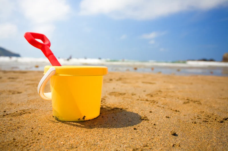 yellow bucket and red spade on a uk beach