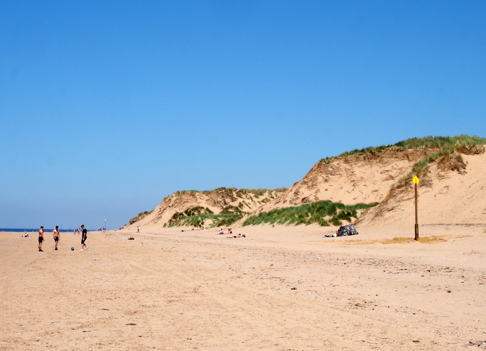 Formby, Merseyside, united kingdom - 28 june 2019: a view of the long sandy beach in Formby Merseyside on a bright summer day with blue sky sand dunes and people sunbathing and playing football