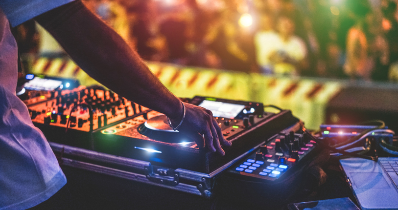 Dj mixing outdoor at new year party festival with crowd of people in background -DJ sets  run throughout the year at Parkdean resorts in England Nightlife view of disco club outside - Soft focus on bracelet, hand - Fun ,youth,entertainment and fest concept