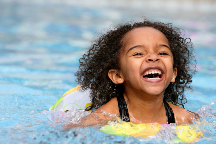 young girl in a rubber ring in a swimming pool smiling