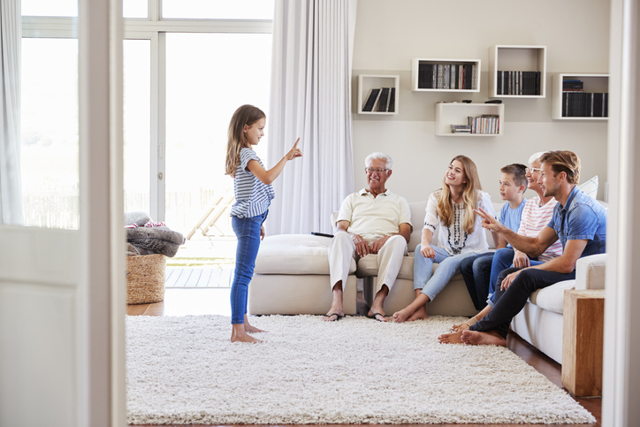 Multi-Generation Family Sitting On Sofa At Home Playing Charades