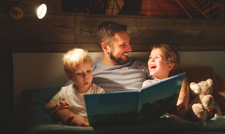 Evening family reading. Father reads children a book before going to bed.