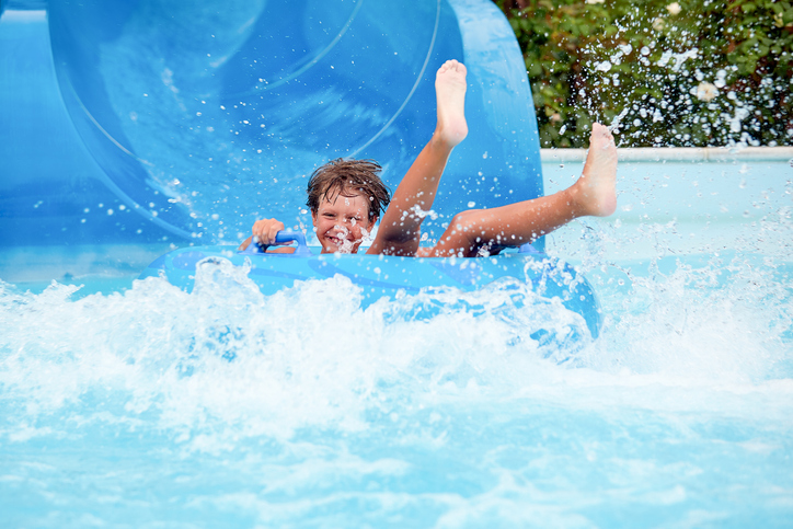 an 8 year old boy is riding in the water Park on inflatable circles on water slides.