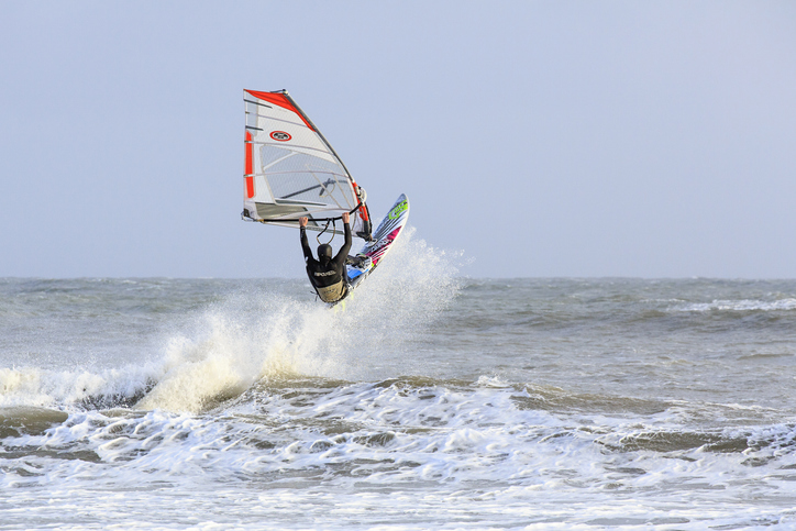 Swansea, UK: February 23, 2016: A windsurfer rides a wave and is airborne.