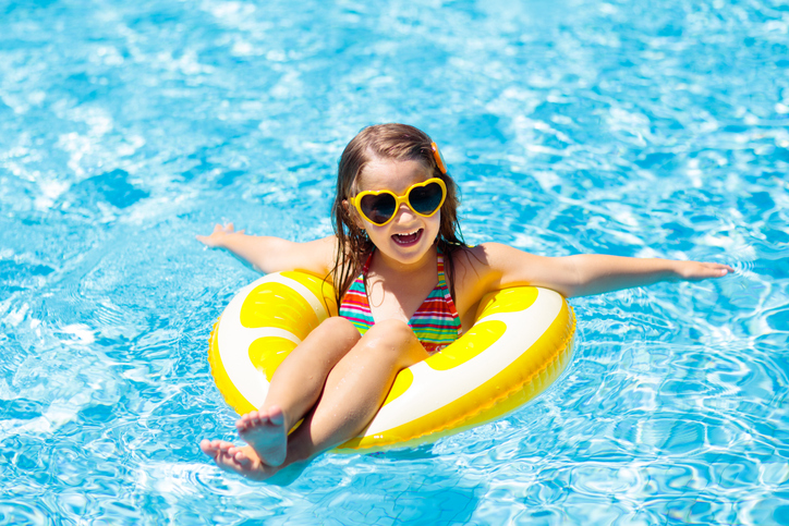 Child in swimming pool on inflatable yellow lemon ring.