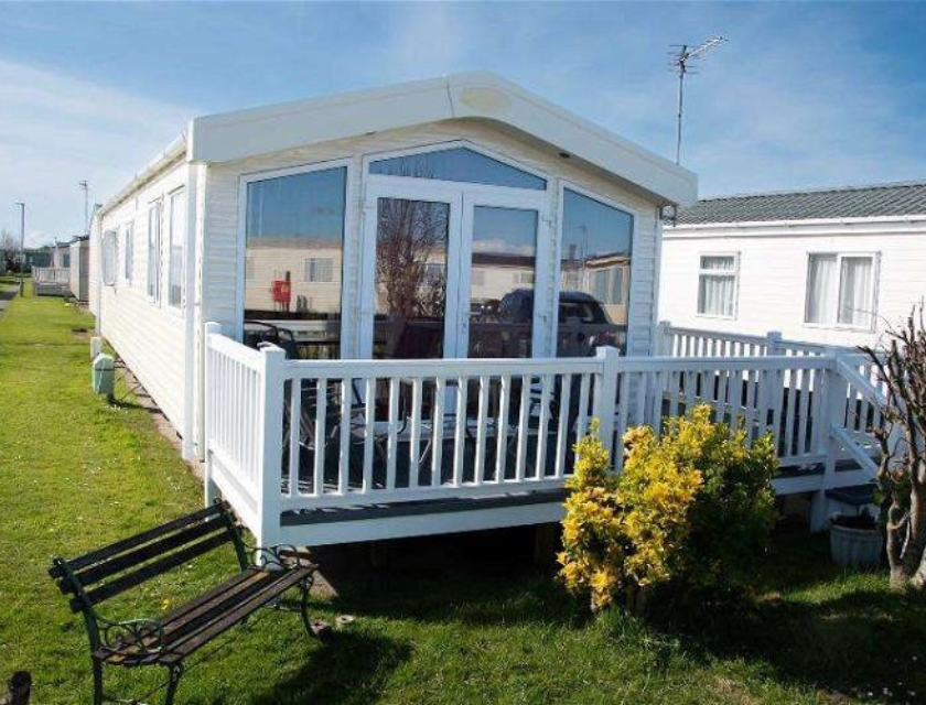 External shot of a static caravan with a bench and grass out front in Whitehouse leisure park in North Wales.