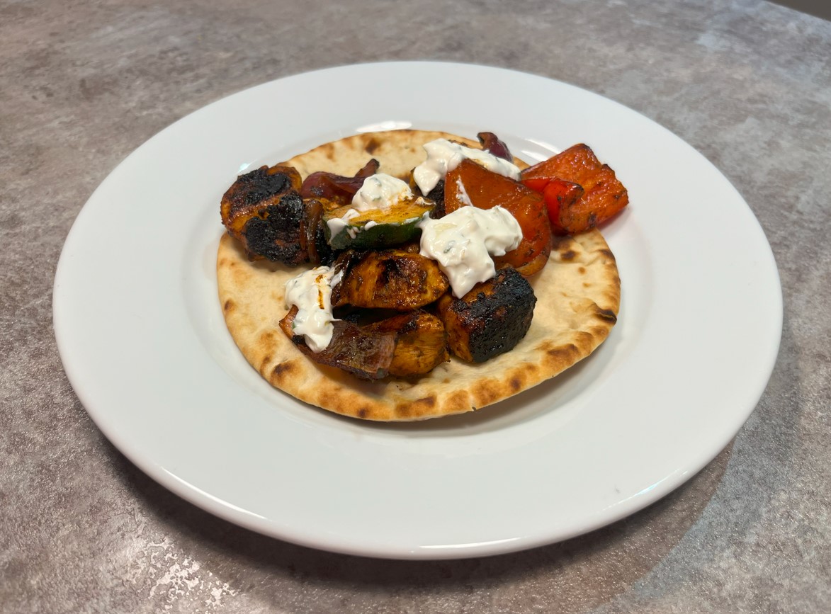 chicken flatbread with peppers, onion and courgette on a white plate