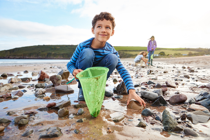 Children Looking In Rockpools On Winter Beach Vacation