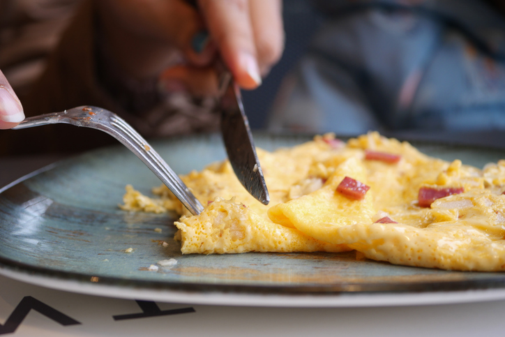 a close up of an omelette being eaten with a knife and fork