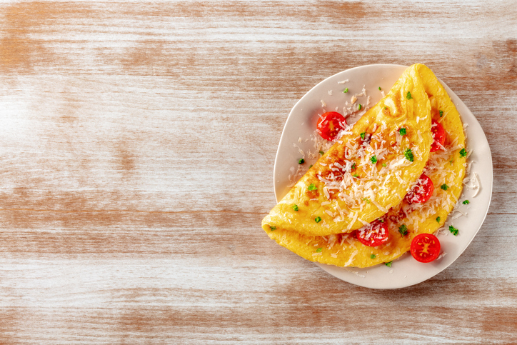 An omelette with tomato and parsley, eggs for breakfast, a healthy vegetarian dish with cheese.