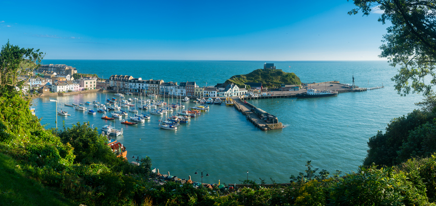 Ilfracombe Harbor in Devon at sunrise in broad panorama across the picturesque town.