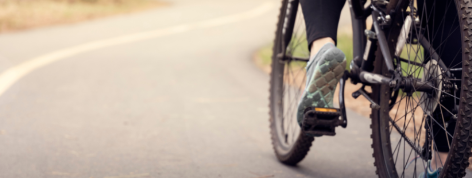 Close-up of a cyclist's foot cycling along a winding path.