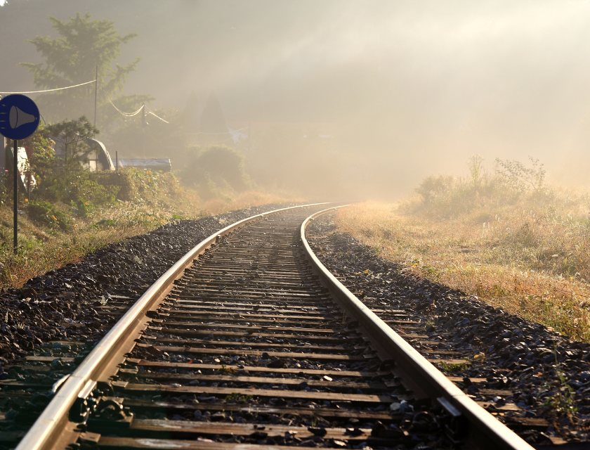 close up shot of a set of train tracks on a misty day. Train tracks fade into the mist which consumes the background.