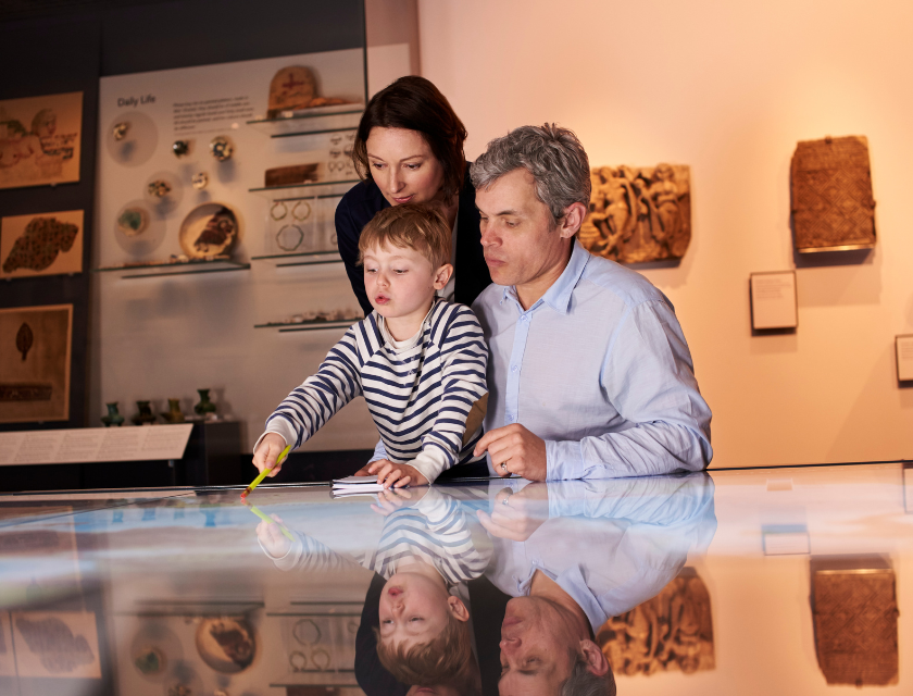 Man and woman with a young boy looking at a museum piece