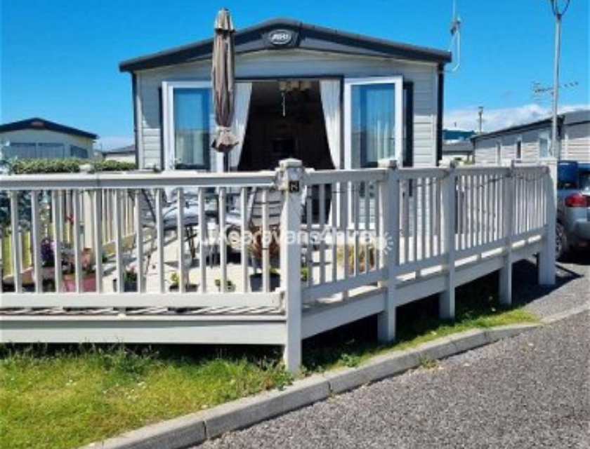 Modern static caravan with white decking and outdoor seating, located in Trecco Bay 
holiday park.