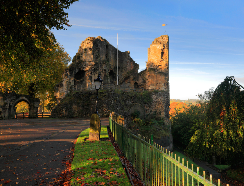 Image taken during sunset of Knaresborough Castle & Courthouse Museum. The sky is blue and clear in the background and the castle casts a shadow in the sunset light.