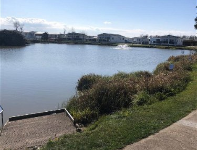 Use Patrington Leisure Park as your base for family days out & activities in Cleethorpes. A lake on Patrington Leisure Park, East Yorkshire. The foreground shows grass and a concrete path, while the background shows clear waters.