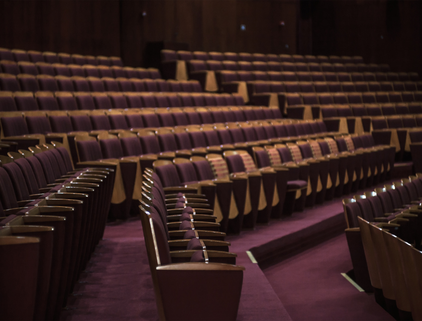 Indoor things to do in Prestatyn. Interior shot of a theater building and the rows of burgundy seats with gold trim.