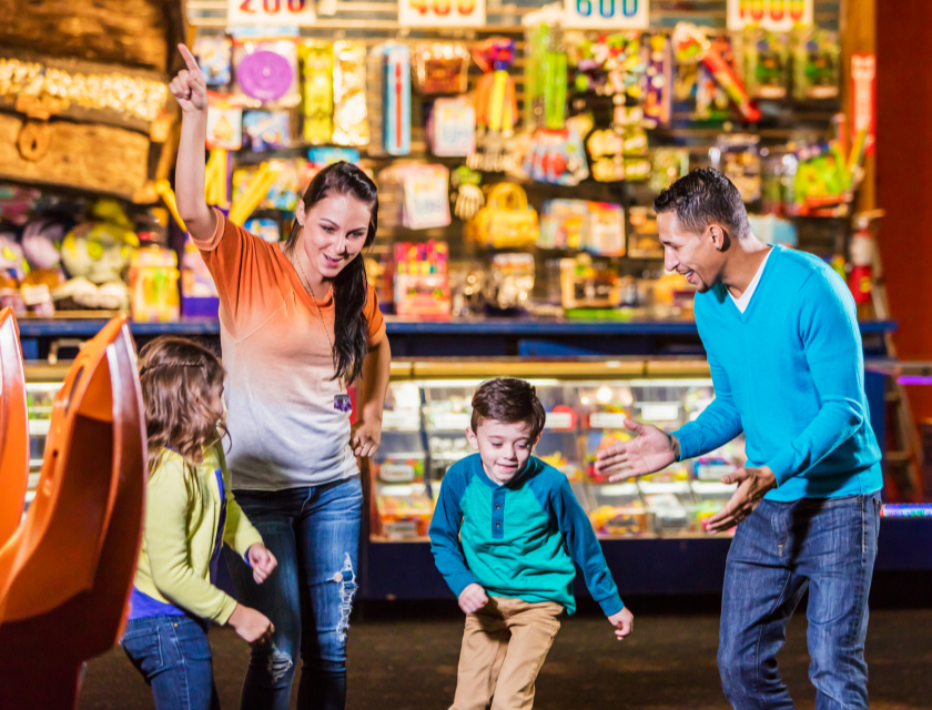 Family with two kids dancing at an arcade. 