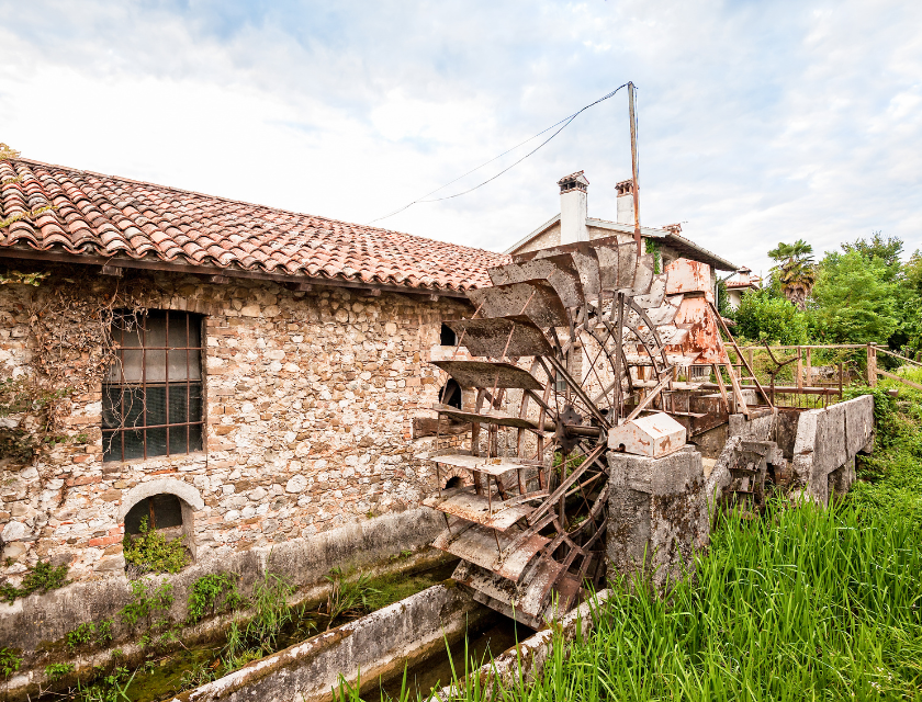 A historic water mill surrounded by greenery, reflecting the cultural heritage and historical sites such as Wheal Martyn Clay Works