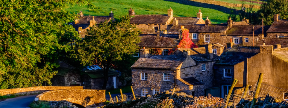 Stone houses in a quiet village at sunset, surrounded by green hills