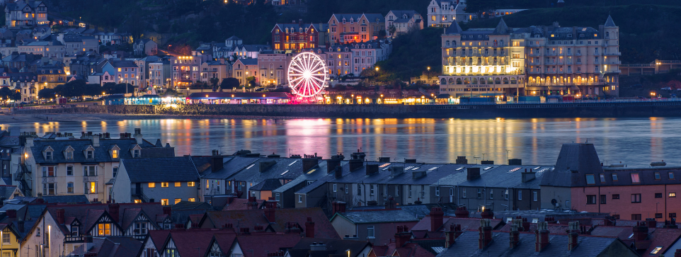 Llandudno illuminated by Christmas lights. A Ferris wheel and seaside promenade provide a festive atmosphere, making it one of the highlights of Christmas markets in North Wales.