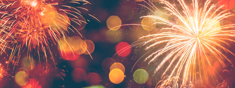 Colourful fireworks at night with bursts of bright red, orange, and yellow lights.