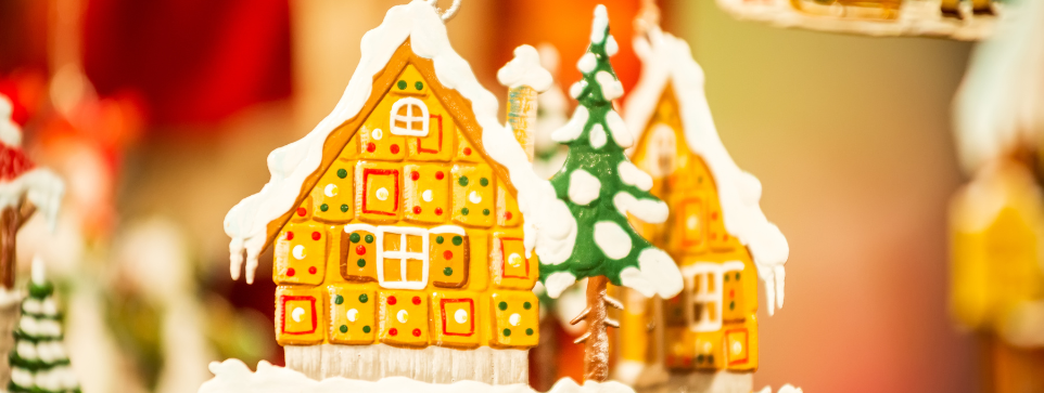 A gingerbread house Christmas decoration hanging at a market.