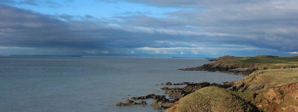 Coastline with dramatic cliffs meeting the sea under a grey sky, perfect for nature lovers exploring glamping sites in the UK.