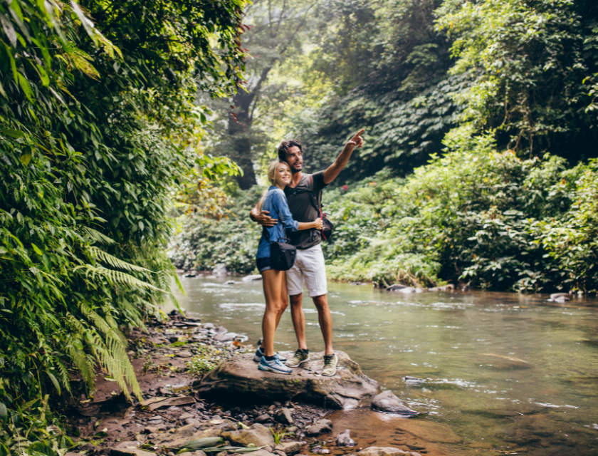 A couple enjoying a scenic forest trail beside a river, ideal for those interested in waterfall walks in North Wales.