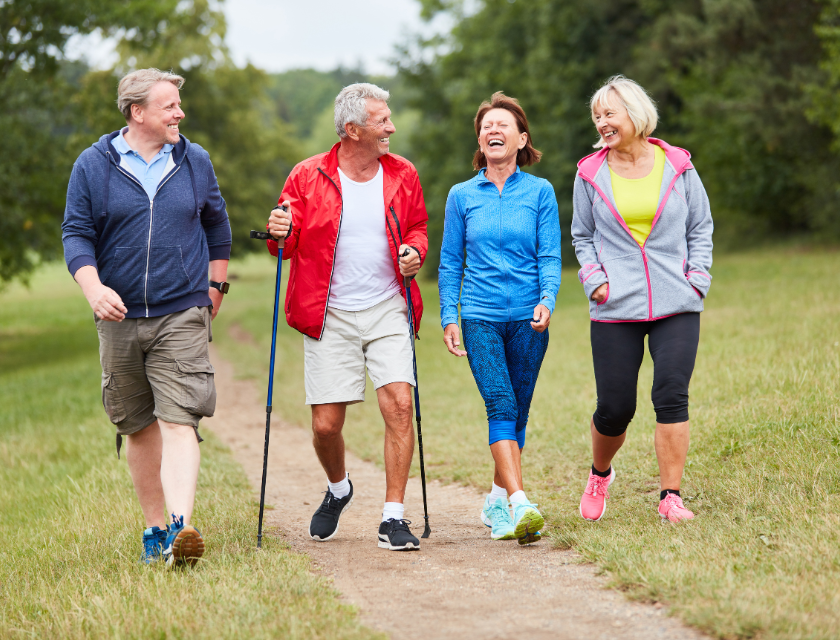 A group of friends smiling as they walk through a green, open landscape. Perfect for social and relaxing walks in Boscastle's countryside.