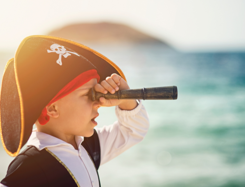 A child dressed as a pirate by the sea.