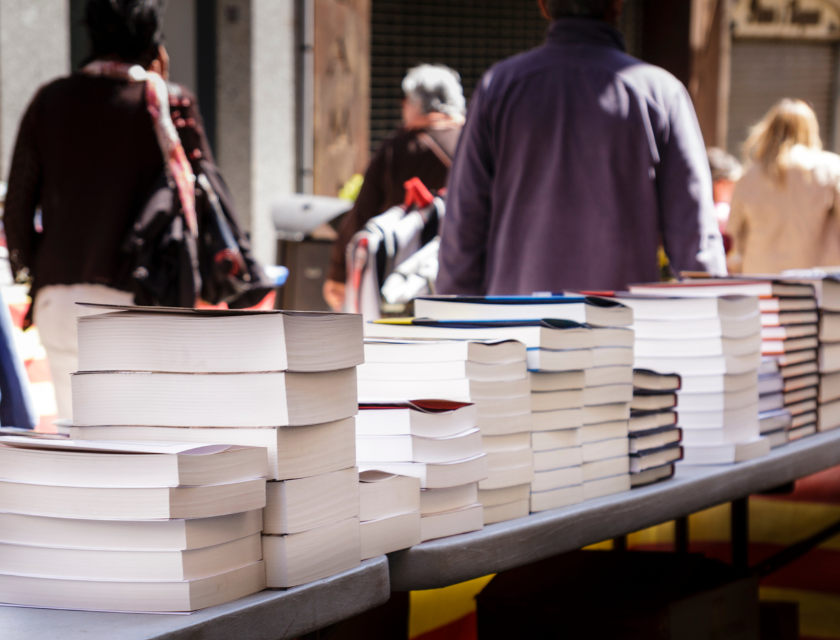 A woman staning infront of a book stall at an outdoor market.