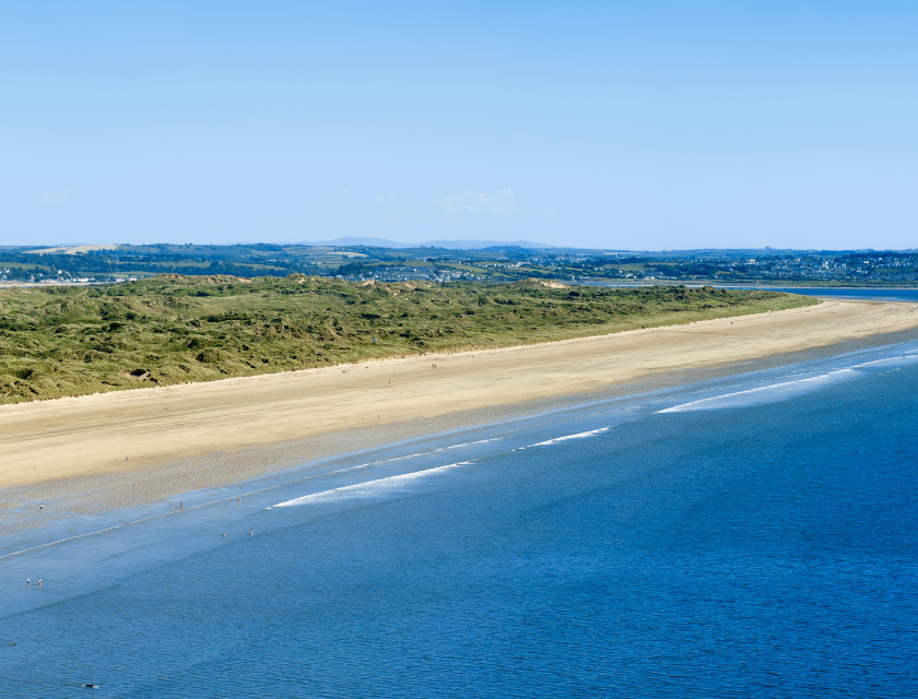 Wide sandy beach with calm blue waters stretching to the horizon