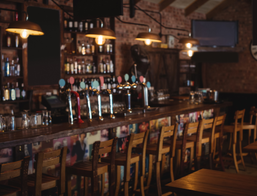 A quiet, pub with a wooden bar and stools, ready for visitors after a day of adventures