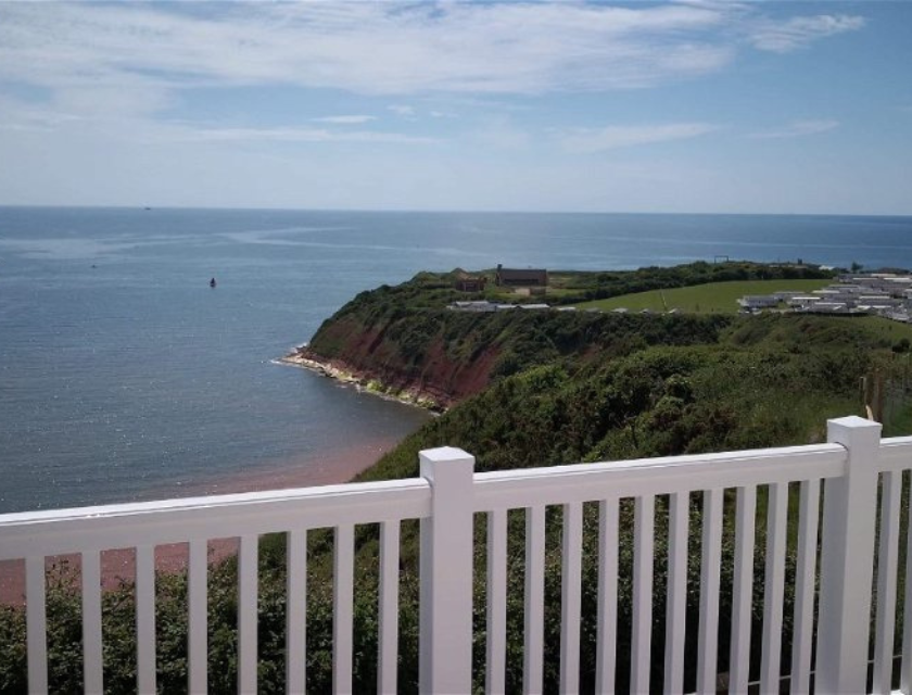 A panoramic view from a white-fenced deck at a dog-friendly caravan park in Devon.