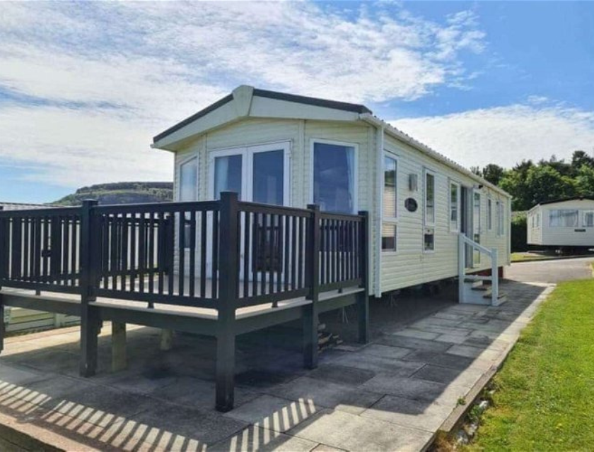 External shot of a static caravan with a private deck at Bron Y Wendon Holiday Park in North Wales.