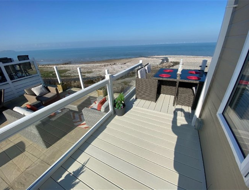 The sea view from a static caravan's deck at The Beach Caravan Park, featuring outdoor seating with views of the beach and coastline.