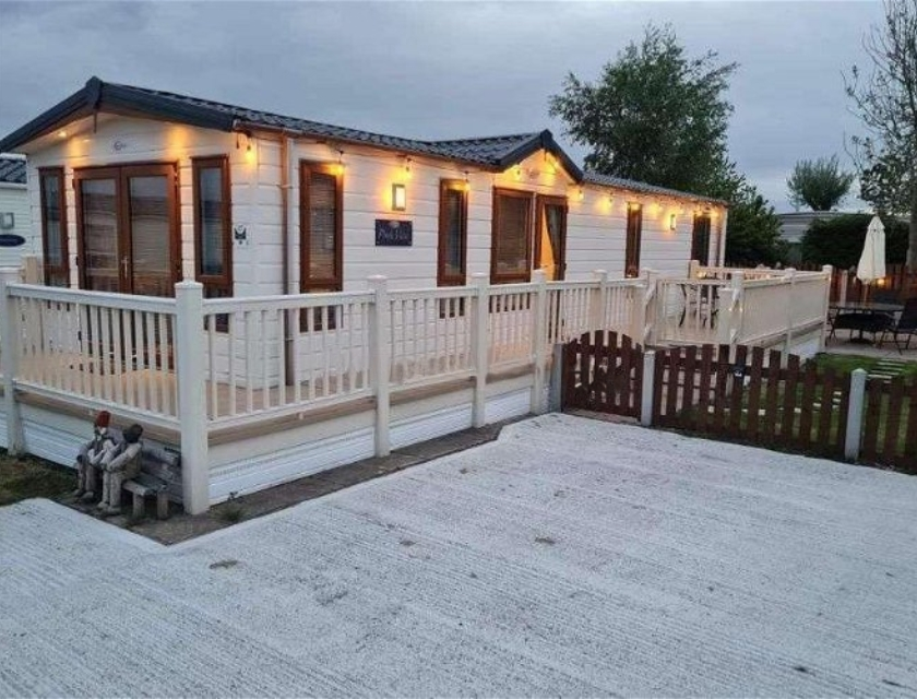 Holiday lodge at Patrington Haven Leisure Park, featuring a wraparound deck, white fencing & outdoor seating. Perfect to use as a base to explore Christmas markets in Yorkshire.