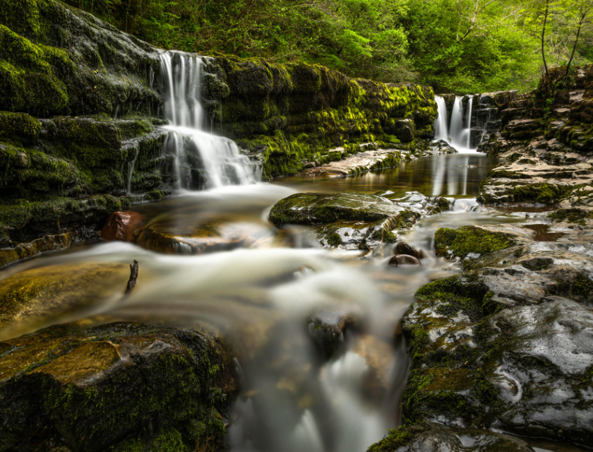 Waterfall surrounded by moss-covered rocks, part of the Four Waterfalls Walk in Wales, a popular spot for winter walks.