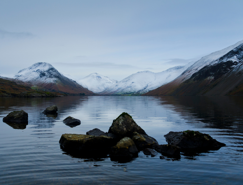 Snow-capped mountains reflected in the still waters of Wast Water, one of the best winter walks in the UK, located in the Lake District.