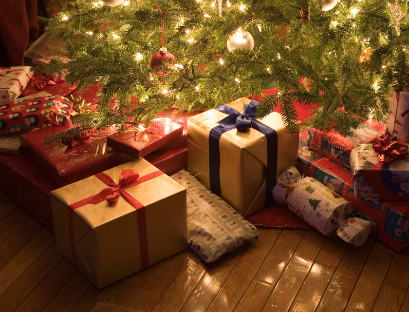 Decorated Christmas tree with gifts wrapped in festive paper underneath.