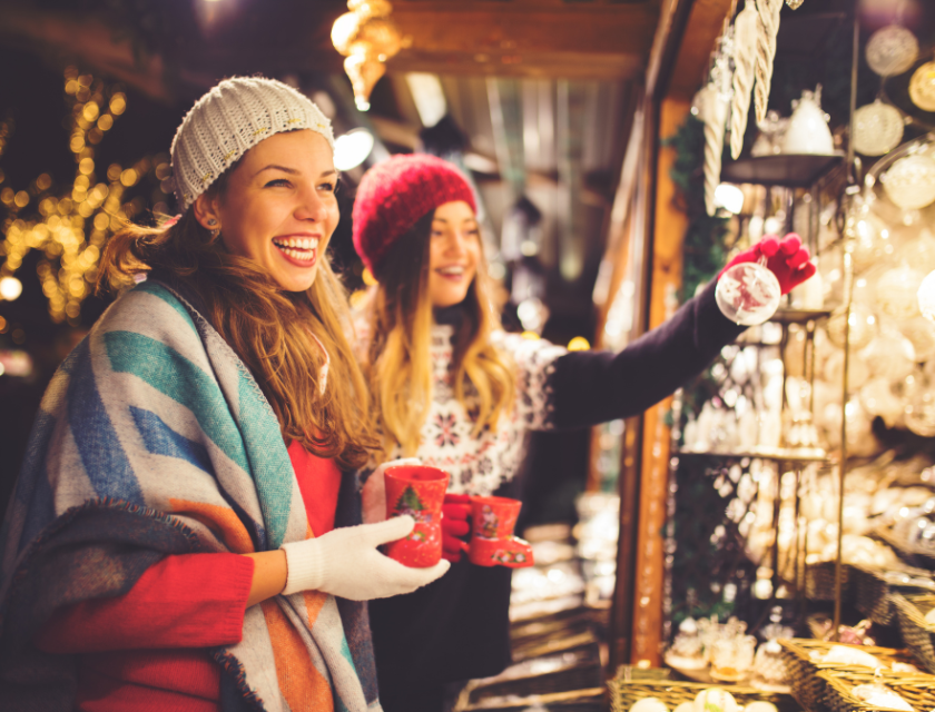 Two female friends enjoying the festive atmosphere at a Christmas market. Common scene when enjoying Christmas markets in Devon,