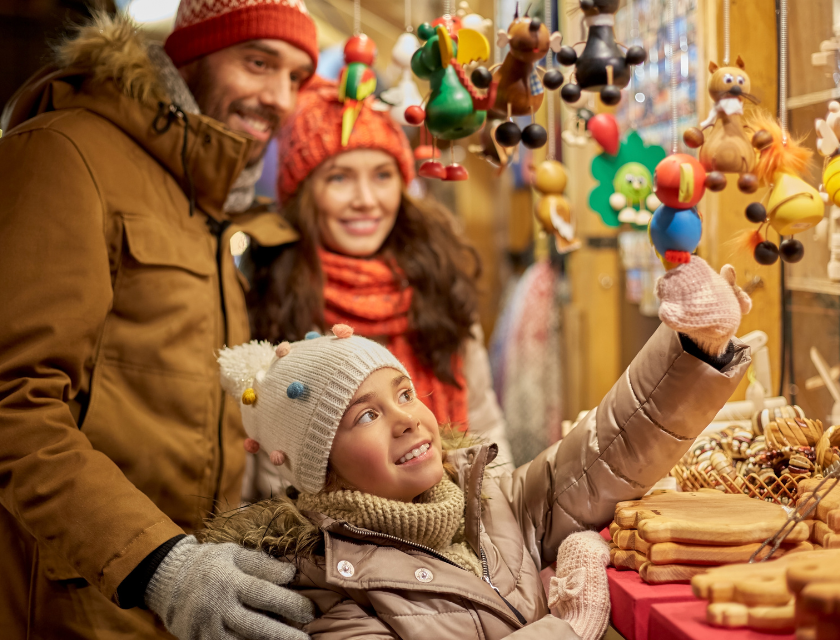 A family enjoying the festive crafts at a Christmas market. Christmas markets in Devon are designed to be family-friendly events.