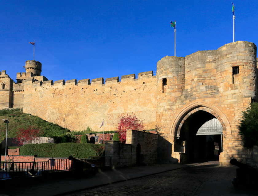 Lincoln castle entrance with flags flying above, in bright daylight.