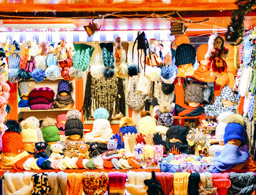 A colourful display of knitted hats, gloves, and scarves at a Christmas market stall.