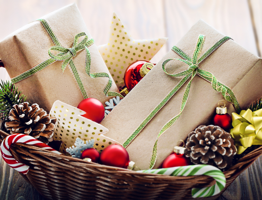 Festive basket filled with wrapped presents, candy canes, and pine cones, tied with green ribbon.